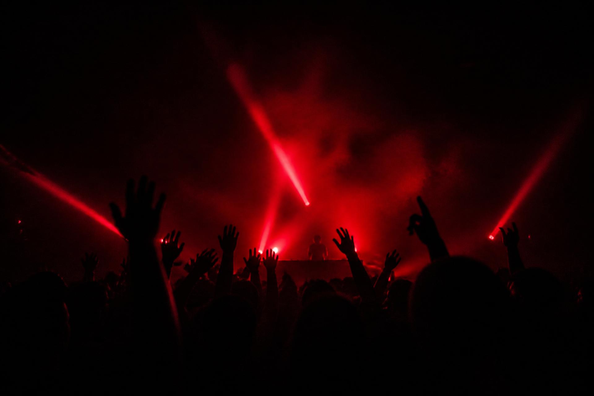 Crowd with raised hands at a 389 Society concert in red stage light